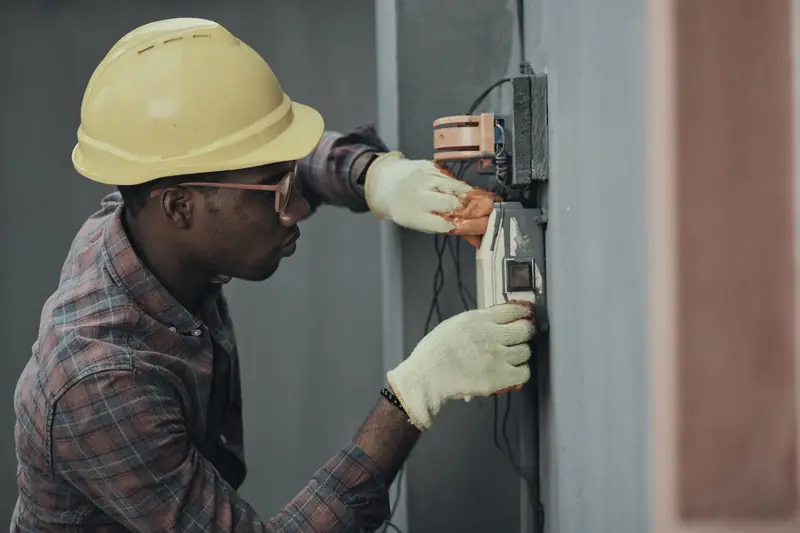 Electrician in a yellow hard hat installing wiring