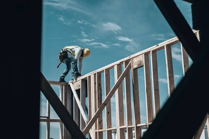 Contractor in a hard hat working on a timber house frame